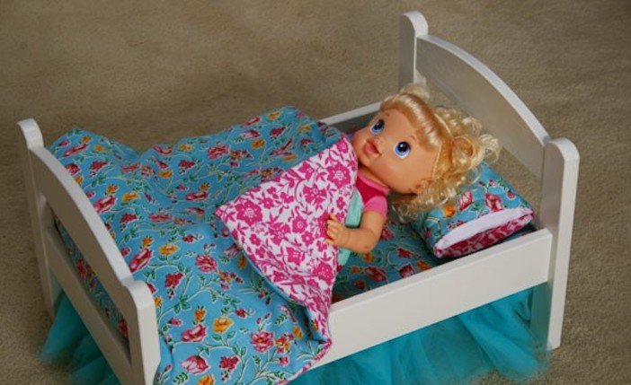 Голая куколка валяется на мягкой кроватке
