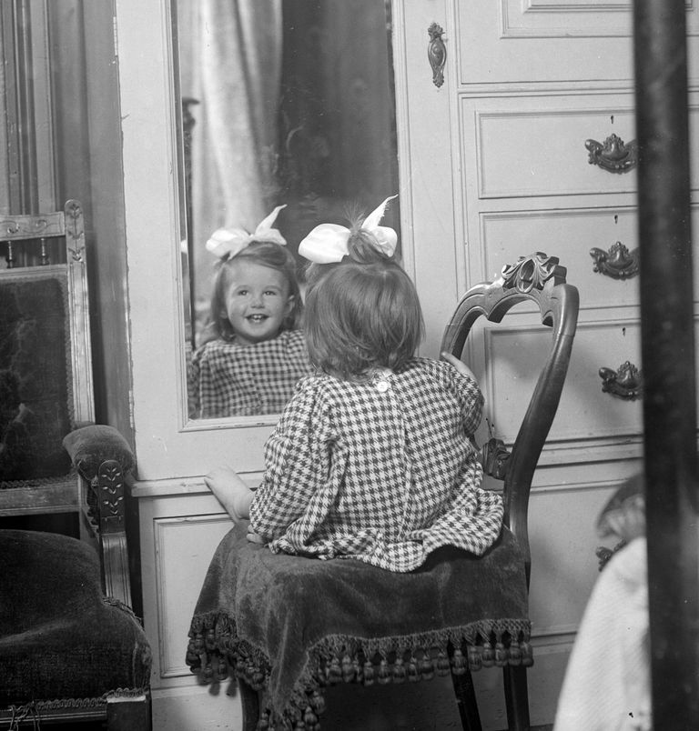 smiling little girl in front of a mirror